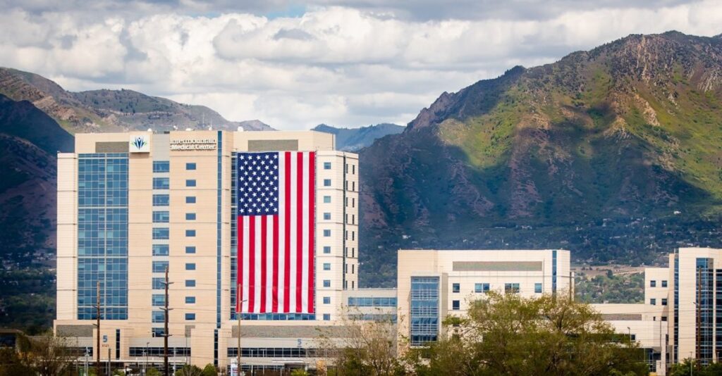 A large American flag hangs on the side of a hospital building to show support to essential medical workers