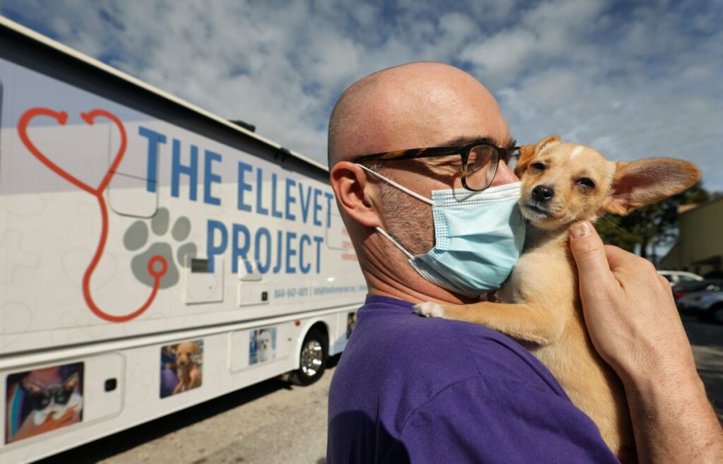ElleVet Project co-founder Christian Kjaer Holding a Dog in Front of the ElleVan.