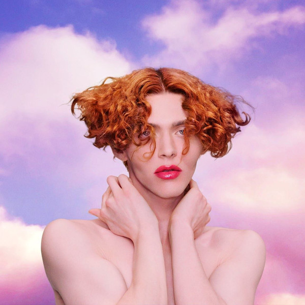 Photo of SOPHIE, a woman with red hair, in front of a pink and purple background with clouds